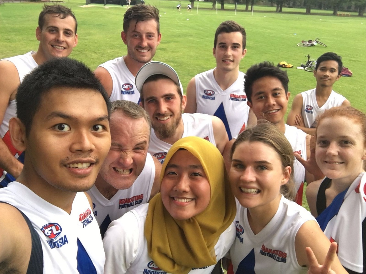 A group of young Australians and Indonesians in sporting gear smile around the camera.