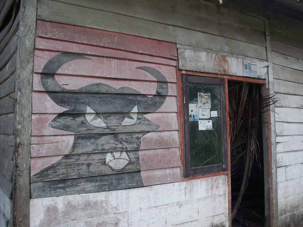 The worn-down, wooden-plank exterior of a house, bare but for a mural of a bull on a red background - PDI-P's symbol. (Laila Kholid Alfirdaus)