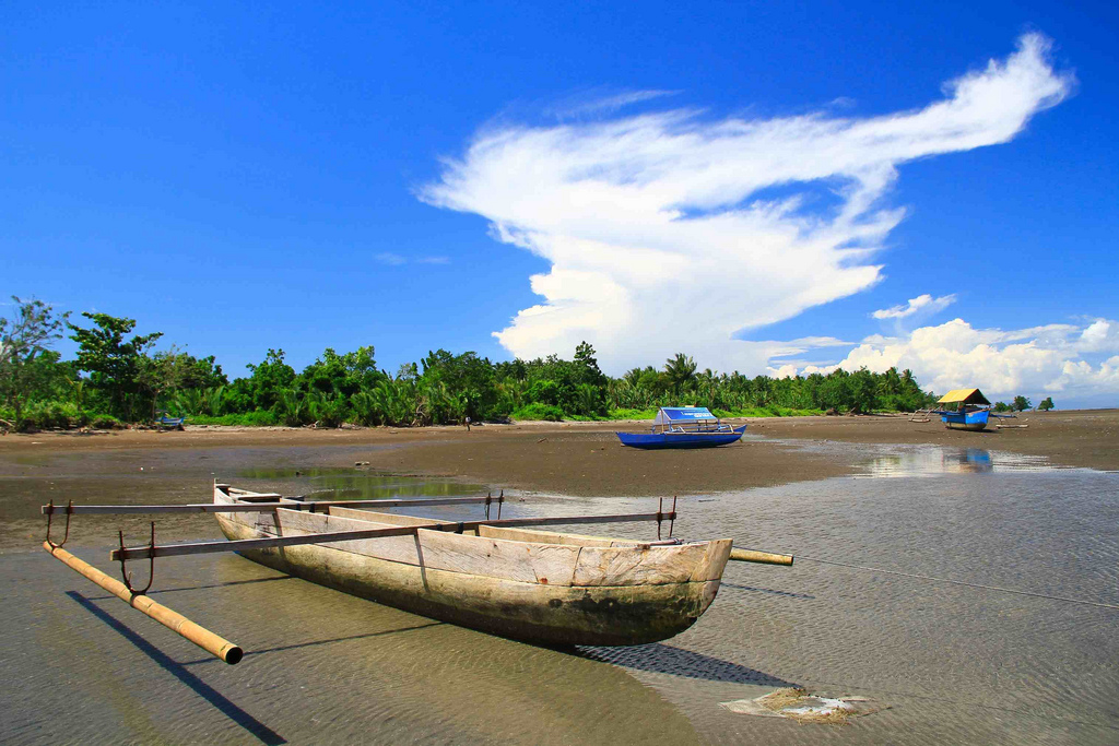 A small wooden boat is docked on the shore, with two others in the background, in Malifut, North Halmahera. (Yefta Christiono)