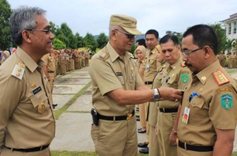 AHM pins a medal to a civil servant standing in line.