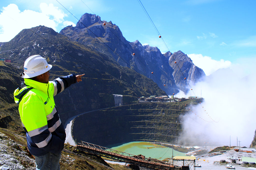 A worker at a mining site points to the low-hanging clouds.