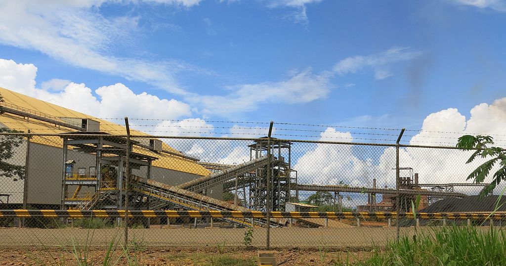 A processing factory behind a tall chain-link fence.