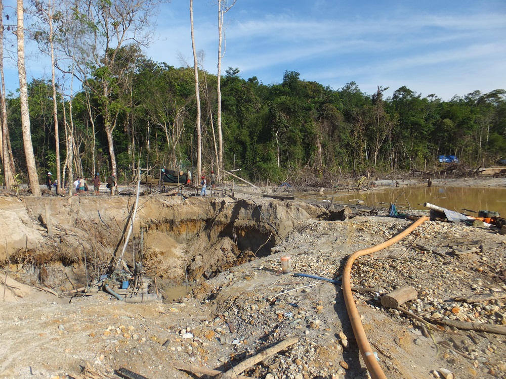 A mining base, with a pipe running across the foreground and some wooden structures.