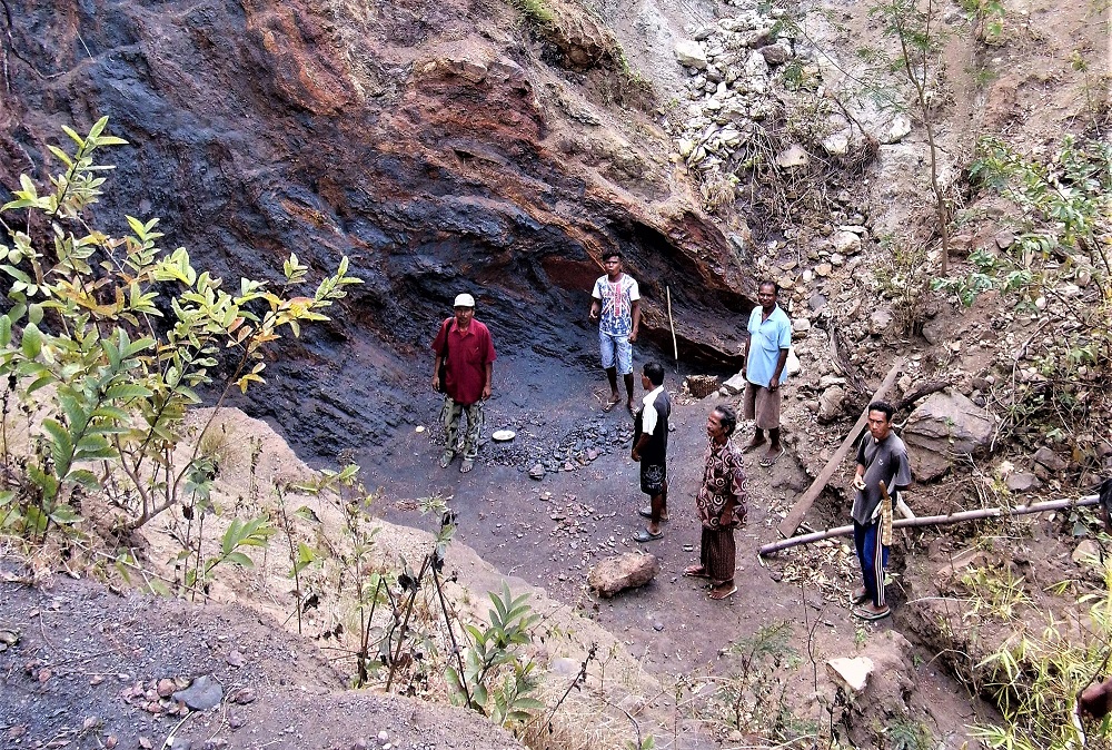 A group of miners stand near a community manganese mine, South Central Timor.