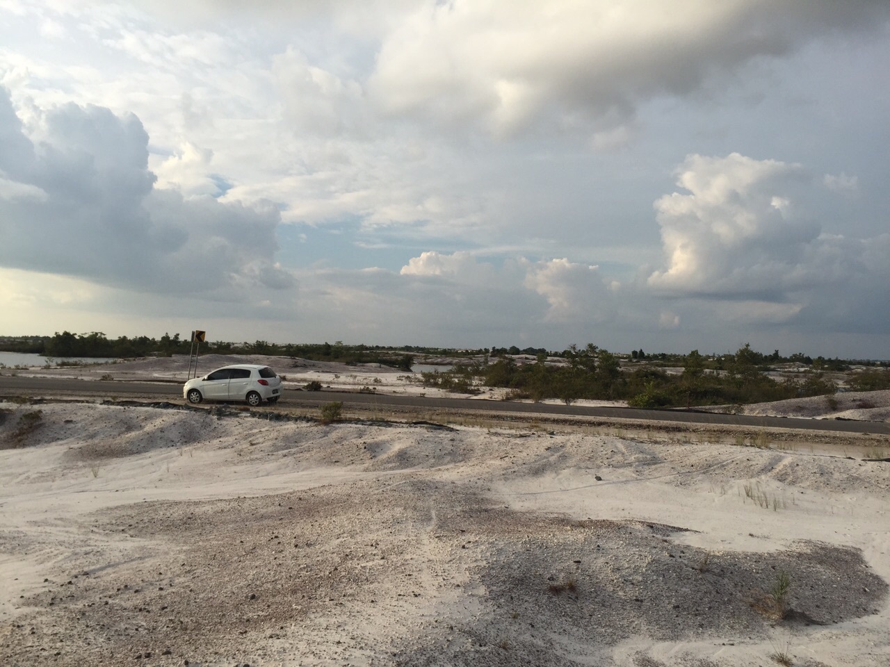 A car zooms by on a road in a barren landscape.