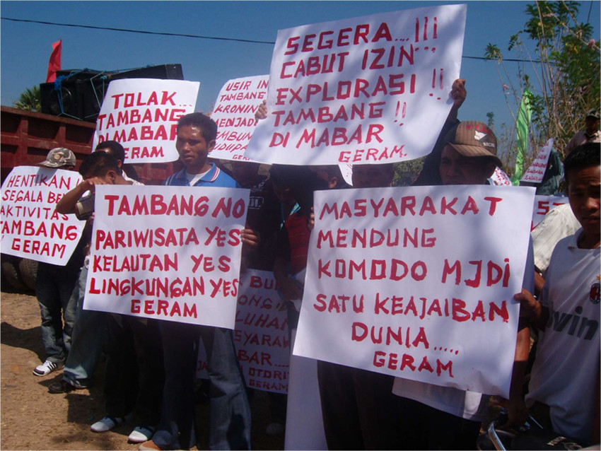 Protestors hold up signs expressing anger at mining activity and exploration.