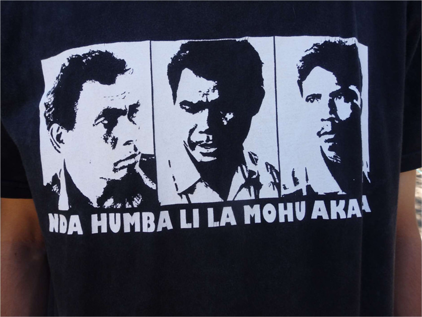 A white print on a black t-shirt, portraying three male faces.