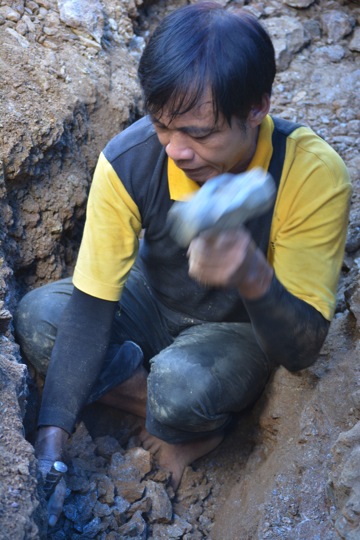 A man mines at the rock with manual tools.